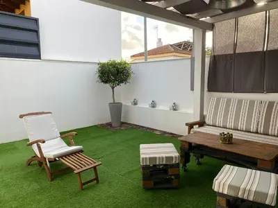 a patio with a bench and a chair and grass at Jerez Deluxe in Jerez de la Frontera