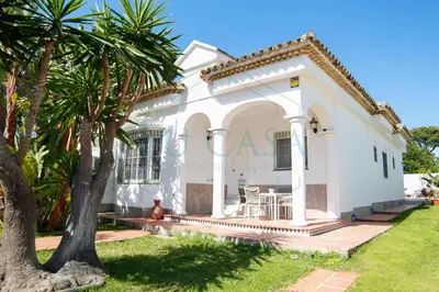 a white house with palm trees in front of it at Villa La Marea in Chiclana de la Frontera