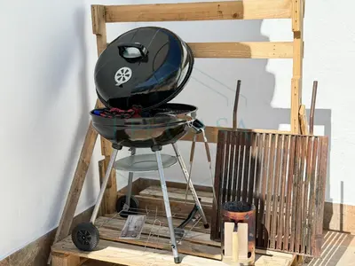 a barbecue grill on a wooden stand next to a wall at Villa La Marea in Chiclana de la Frontera