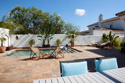 a patio with two chairs and a swimming pool at Villa La Marea in Chiclana de la Frontera