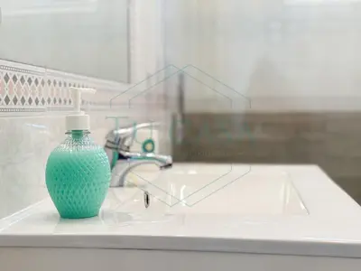 a green glass bottle sitting on a bathroom sink at Villa La Marea in Chiclana de la Frontera