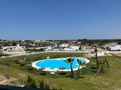 a swimming pool with umbrellas and a resort at Apartamento Sanlúcar PARKING GRATIS ,PISCINA ,WIFI ATICO con vistas in Sanlúcar de Barrameda