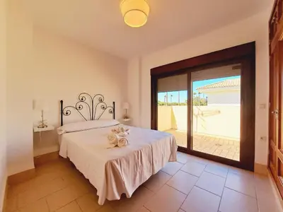 a bedroom with a bed and a large sliding glass door at Chalet Loma de Sanctipetri in Chiclana de la Frontera