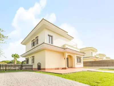a white house with a fence and grass at Chalet Loma de Sanctipetri in Chiclana de la Frontera
