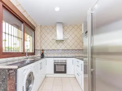 a kitchen with white cabinets and a refrigerator at Chalet Loma de Sanctipetri in Chiclana de la Frontera