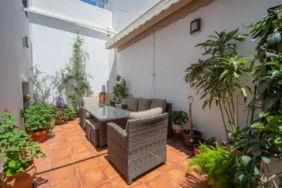 a patio with a couch and a table and plants at La Casa de los Girasoles in Cádiz