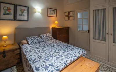 a bedroom with a bed with a blue and white comforter at La Casa de los Girasoles in Cádiz