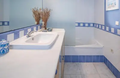 a bathroom with a white sink and a tub at La Casa de los Girasoles in Cádiz
