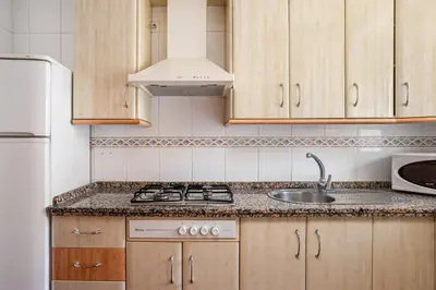 a kitchen with wooden cabinets and a sink and a refrigerator at aldea 2 5 1ºB in Chiclana de la Frontera