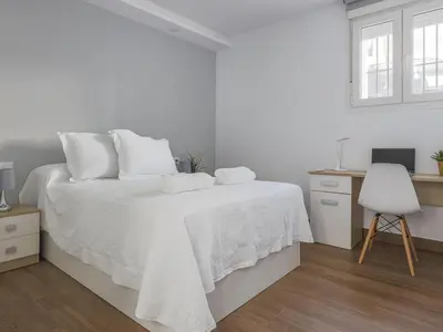 a white bedroom with a white bed and a white chair at Playa Caleta in Cádiz