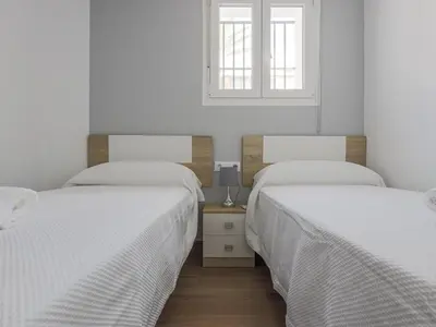 two beds in a white room with a window at Playa Caleta in Cádiz