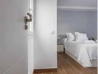 a white bedroom with a bed with white sheets at Playa Caleta in Cádiz