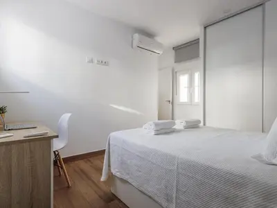 a white bedroom with a bed and a desk at Playa Caleta in Cádiz