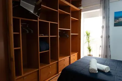 a bedroom with a bed and a large wooden closet at Apartalux Playa La Caleta in Cádiz