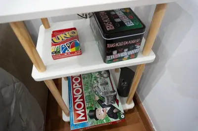 a small white shelf with games and books on it at Apartalux Playa La Caleta in Cádiz