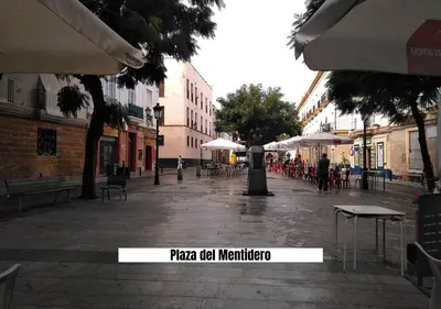 an empty street with tables and umbrellas in a city at Apartalux Playa La Caleta in Cádiz