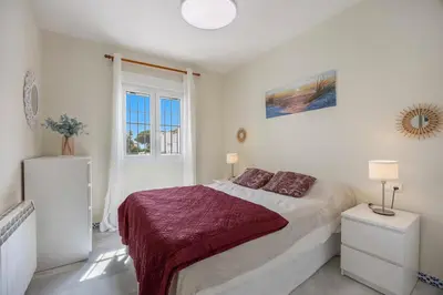 a white bedroom with a large bed and a window at Magnifico apartamento en la Barrosa frente al mar in Novo Sancti Petri
