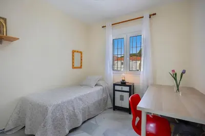 a bedroom with a bed and a table and a window at Magnifico apartamento en la Barrosa frente al mar in Novo Sancti Petri