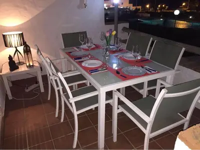 a white table with white chairs and a table with wine glasses at Magnifico apartamento en la Barrosa frente al mar in Novo Sancti Petri