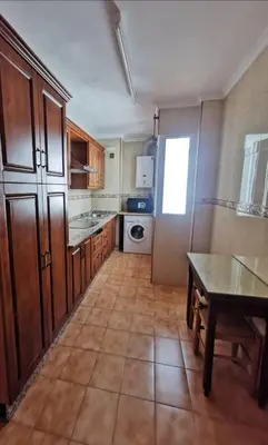a large kitchen with wooden cabinets and a table at Great apartment in Puerto Real in Puerto Real