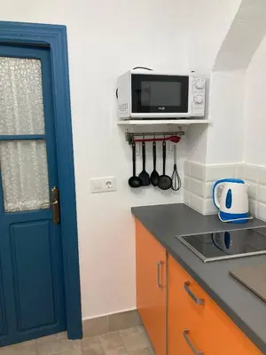 a kitchen with a blue door and a microwave at Charming 1900 Andalusian Apartment in Arcos de la Frontera in Arcos de la Frontera