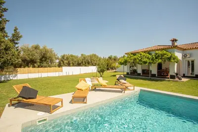 a backyard with a pool with chairs and a house at Jardines Fenicios Luxurious and Spacious Villa in Novo Sancti Petri