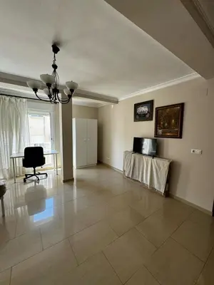 an empty living room with a table and a television at Velo de Flor Jerez Apartment in Jerez de la Frontera