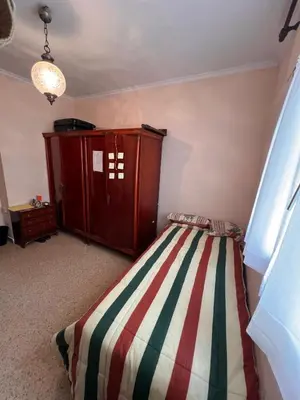 a bedroom with a bed and a wooden cabinet at San José Playa Family Home in Cádiz