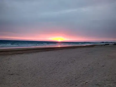 a sunset on a beach with the ocean at San José Playa Family Home in Cádiz