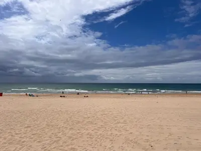 a beach with people on the sand and the ocean at San José Playa Family Home in Cádiz