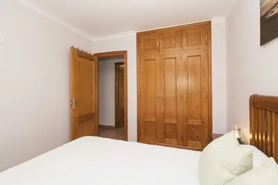 a bedroom with a bed and wooden cabinets at Novo Golf Chiclana in Chiclana de la Frontera