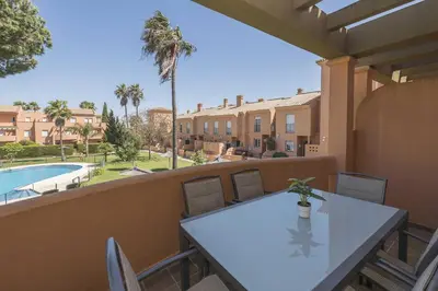 a table on a balcony with a view of a pool at Novo Golf Chiclana in Chiclana de la Frontera