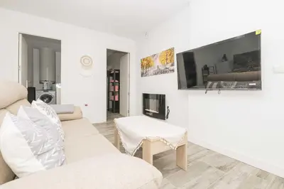 a white living room with a couch and a tv at Apartamento Tom-Isi in Rota
