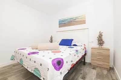 a bedroom with a large bed in a white room at Apartamento Tom-Isi in Rota