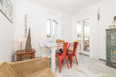 a white dining room with a table and chairs at Estribor in Poblado de Sancti Petri