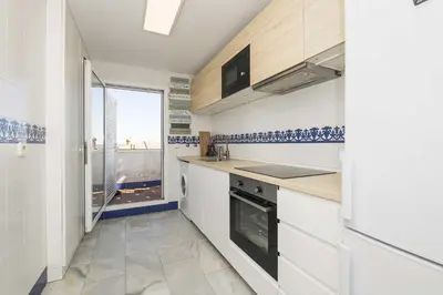 a kitchen with white cabinets and a large window at Estribor in Poblado de Sancti Petri