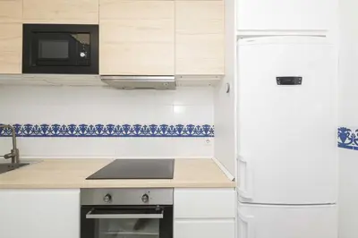 a white kitchen with a refrigerator and a microwave at Estribor in Poblado de Sancti Petri