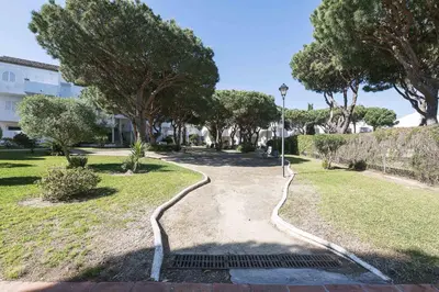 a walkway in a park with trees and a street light at Estribor in Poblado de Sancti Petri