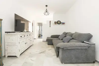 a living room with a gray couch and a tv at Estribor in Poblado de Sancti Petri