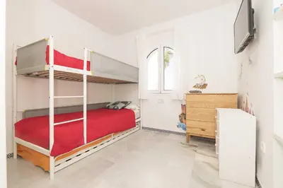 a bedroom with two bunk beds and a tv at Estribor in Poblado de Sancti Petri