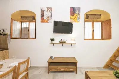 a living room with a table and a tv on a wall at Loft Santiago in Jerez de la Frontera