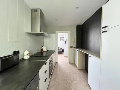 a kitchen with black countertops and a white refrigerator at Apartamento Luz de Chiclana by Come2Cádiz in Chiclana de la Frontera