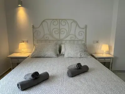 a bed with two towels on it with two lamps at Apartamento Canalejas in Cádiz