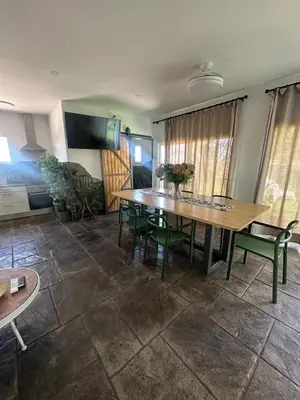 a dining room with a wooden table and green chairs at Villa Rural Nuestro Rincón in Sanlúcar de Barrameda