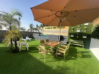 a patio with a table and chairs and an umbrella at Villa Rural Nuestro Rincón in Sanlúcar de Barrameda