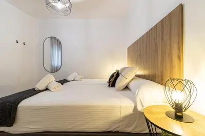 a bedroom with a large white bed and a table at Allo Apartments Balderrama Parking Centro 1 Habitación in Jerez de la Frontera