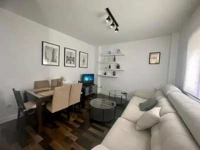 a living room with a couch and a table with a television at Solera y Mar, Apartamentos Living Sur in Sanlúcar de Barrameda