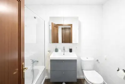 a white bedroom with a bed and a mirror at Solera y Mar, Apartamentos Living Sur in Sanlúcar de Barrameda