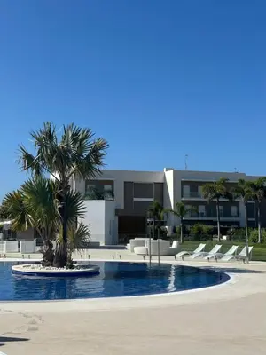 a pool with chairs and a palm tree in front of a building at Eleven Views in Chipiona