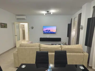 a living room with a couch and a tv on the wall at García Rota Beach by staycare in Rota